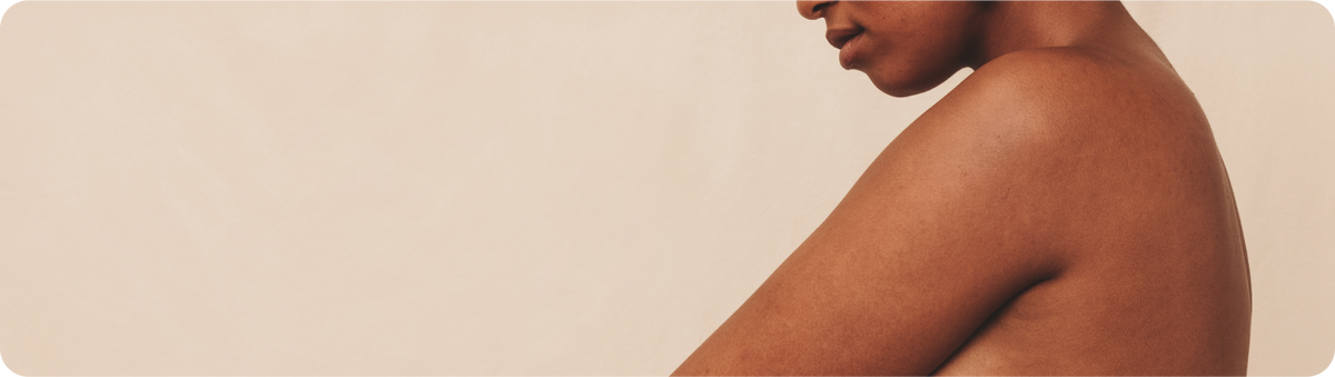 Close-up of a woman's bare shoulder and back against a neutral background, representing women's health and body wellness