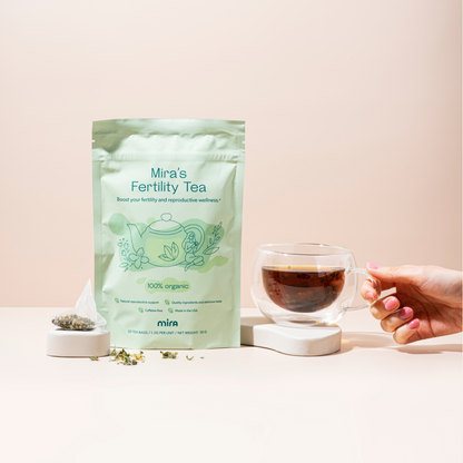 Mira's Fertility Tea package with loose tea in a small bowl and a hand holding a cup of brewed tea.