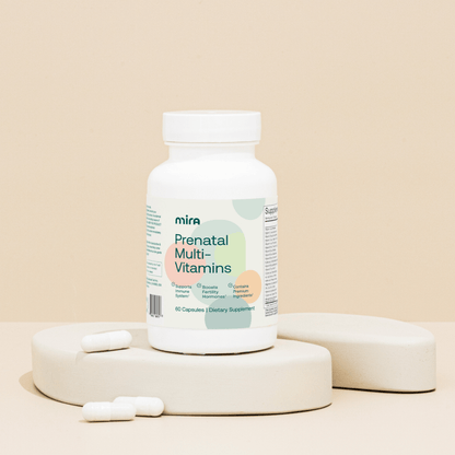 White bottle of Mira Prenatal Multi-Vitamins with white capsules displayed on beige platform.