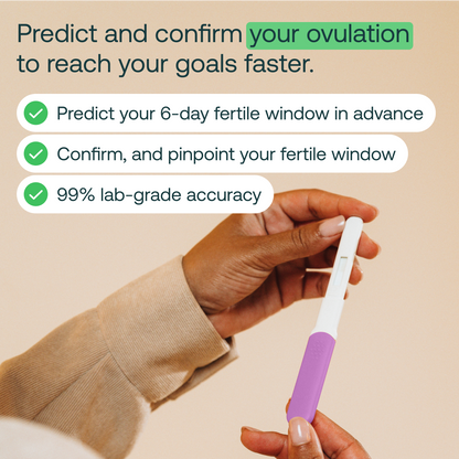 Hand holding white ovulation test wand with purple grip against beige background.