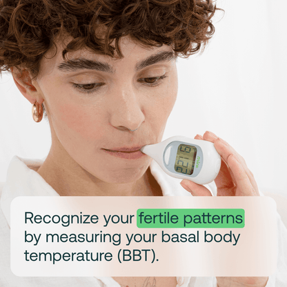 Person holding white digital thermometer with LCD display showing temperature reading near face.