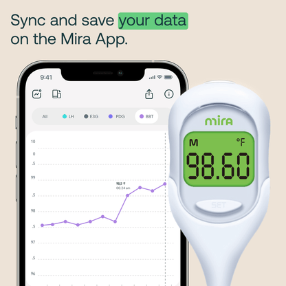 White Mira basal body thermometer displaying 98.60°F on green screen, next to smartphone showing temperature tracking app wit