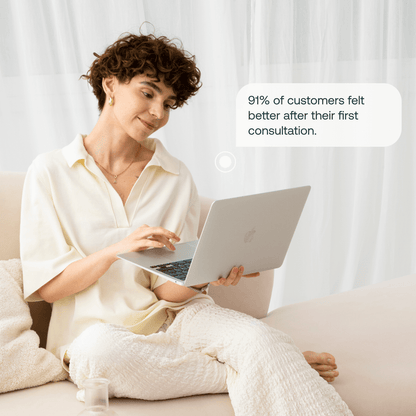 Woman with short brown curly hair wearing cream-colored shirt using laptop with customer testimonial speech bubble.