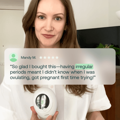 Woman holding white circular hormone monitor device with digital display screen.