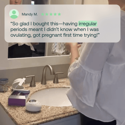 White hormone monitoring device with purple packaging on bathroom counter next to sink.