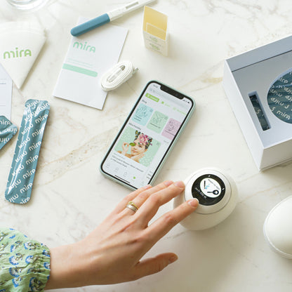 Mira Starter Kit contents displayed on marble surface including smartphone with app, white device, instruction cards, USB cab