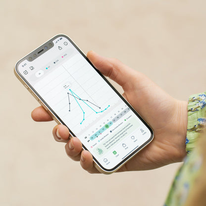 Hand holding smartphone displaying Mira app interface with graph and data tracking on screen.