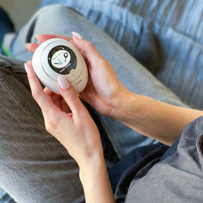 Hand holding white circular device with dial display and "mira" branding.