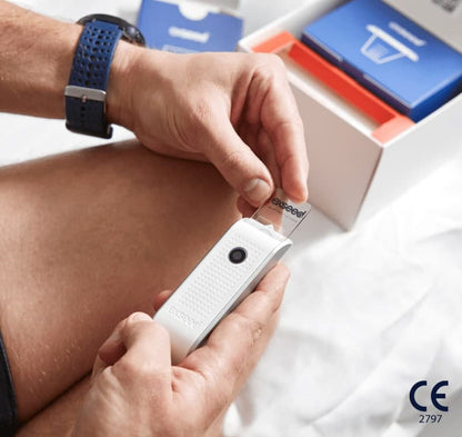 Hand holding white ExSeed Sperm 2 test device with small lens, blue and red packaging visible in background.